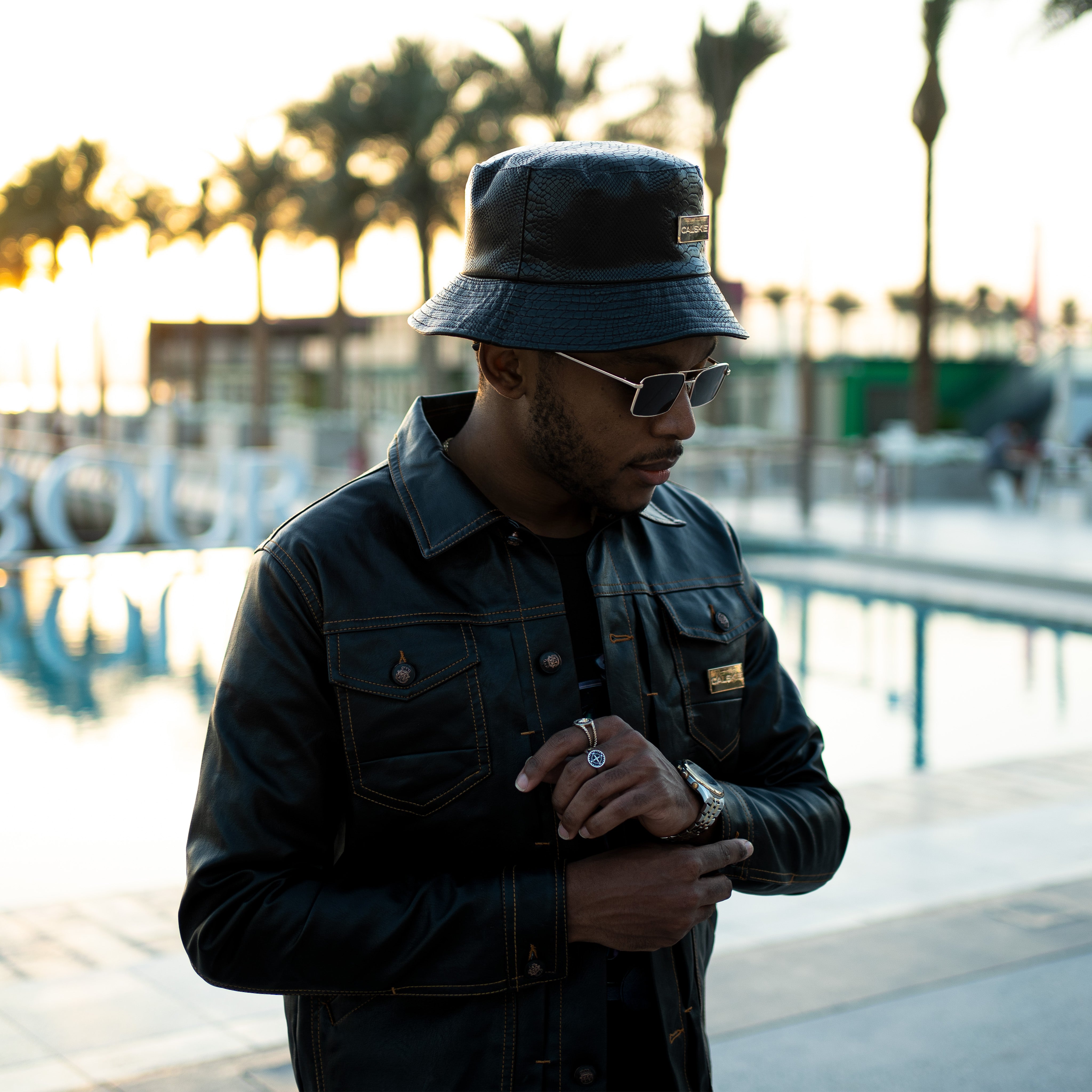 An image showing the black crocodile pattern leather bucket hat by Calskie, featuring the gold Calskie logo on the front.