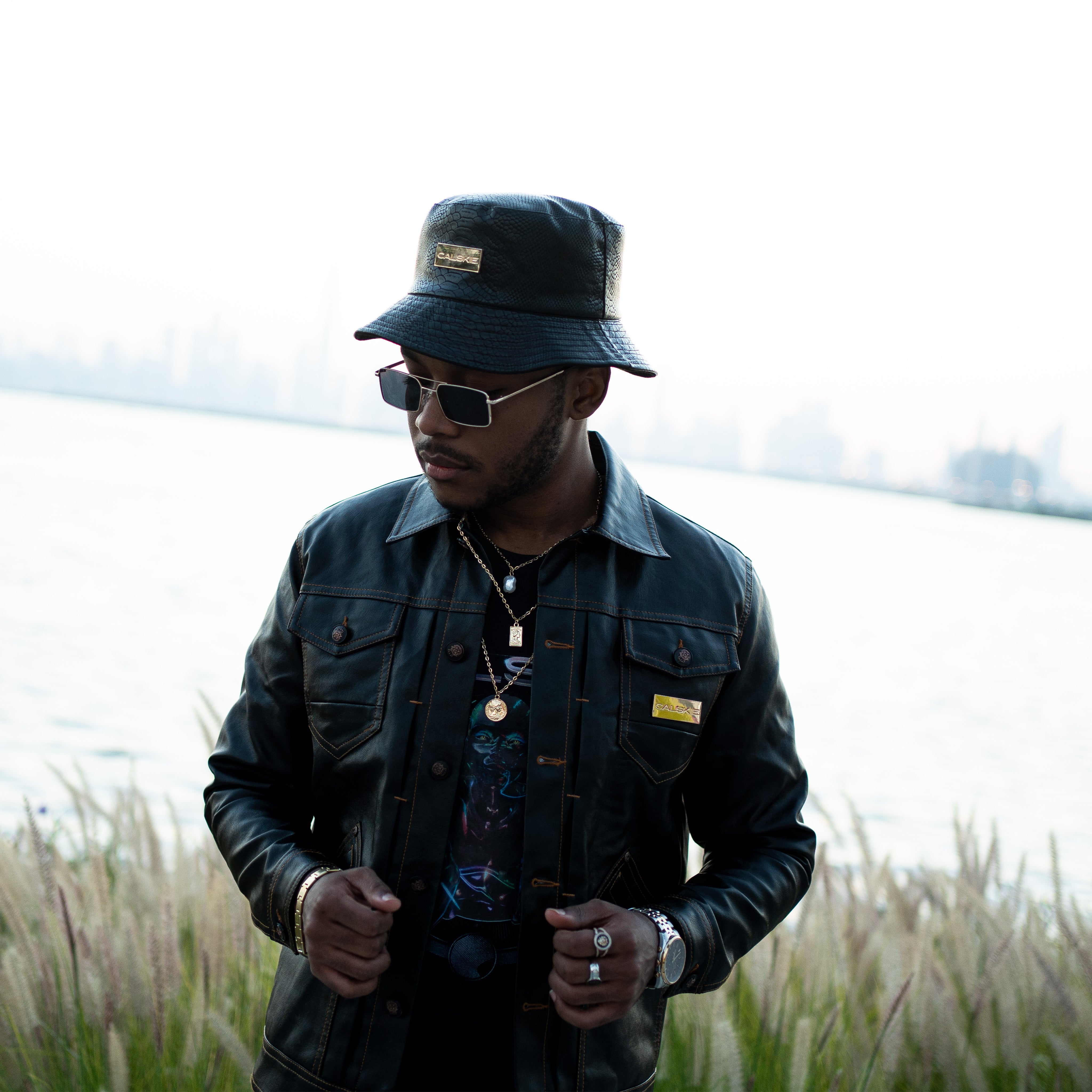 An image showing the black crocodile pattern leather bucket hat by Calskie, featuring the gold Calskie logo on the front.